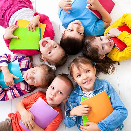 Six kids with books lying on the floor together. Top view Six kids with books lying on the floor together. Top view